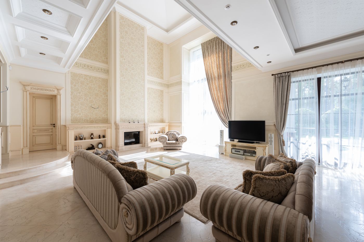 Bright double-height living room with cream painted walls and cornices