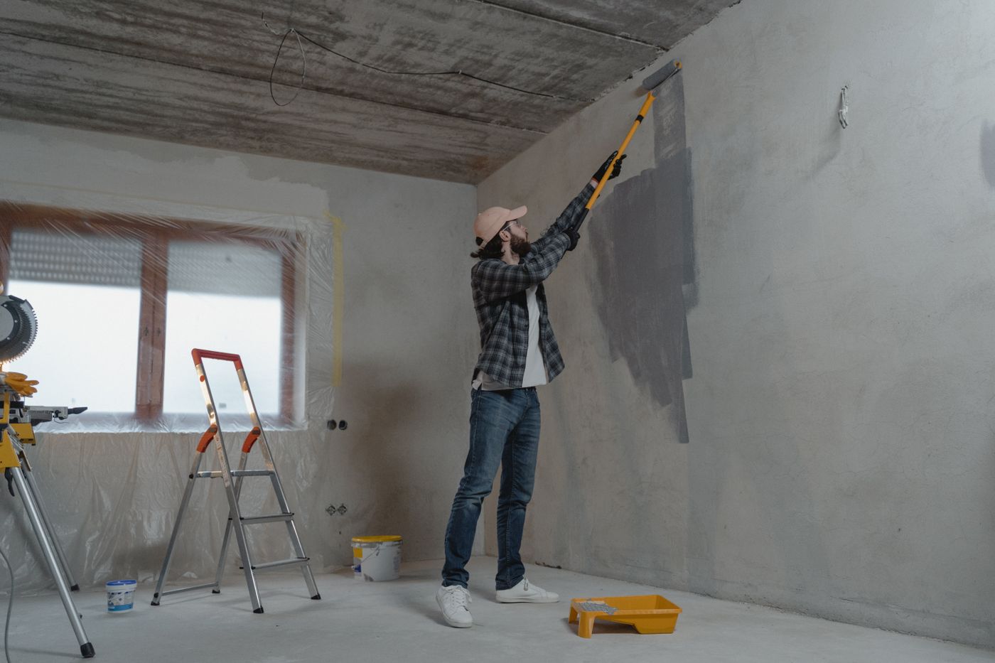 Painter working a roller across a prepared interior wall
