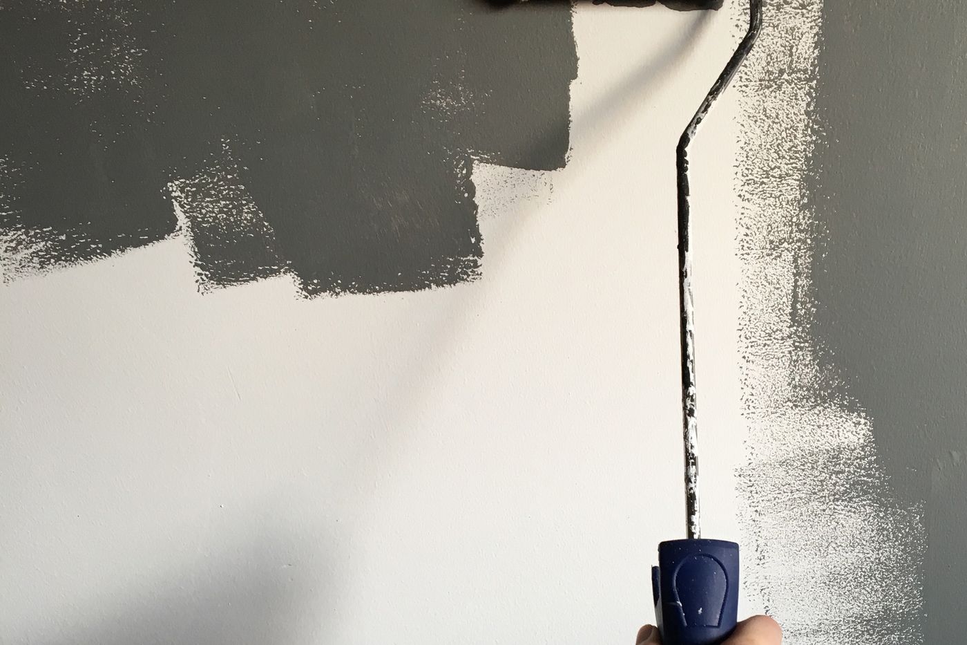 Close view of a paint roller laying a fresh coat onto a wall